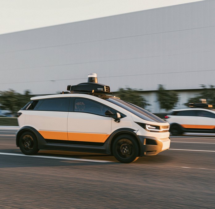 Two autonomous cars on a road at dusk.